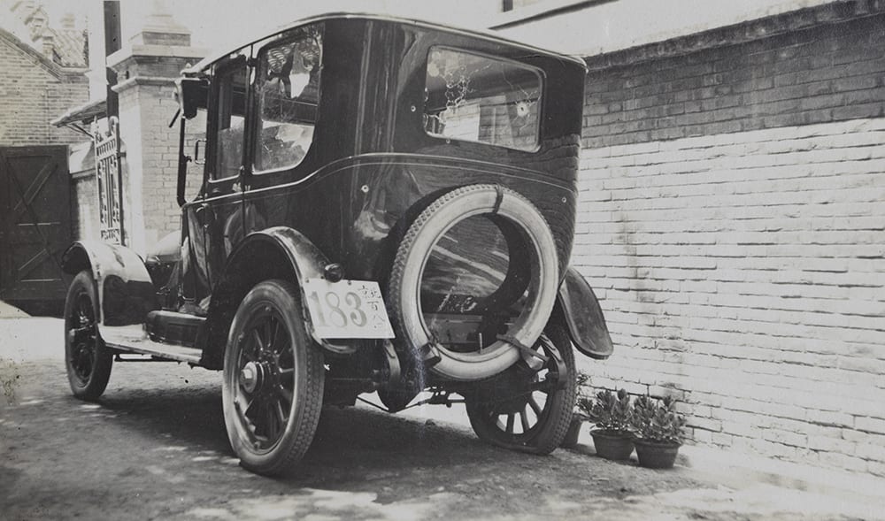 Guy Hillier’s car parked outside the premises of the Hongkong and Shanghai Bank, Beijing, with flat tyres, broken windscreen, broken windows, and bullet holes. Richard Family Collection, Historical Photographs of China ref EH01-243.