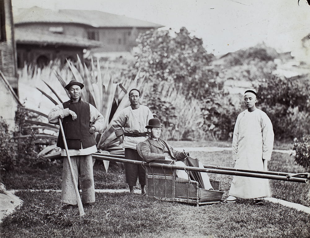 John Gurney Fry is depicted, somewhat idiosyncratically, with bowler and umbrella, in a sedan chair parked in the garden of ‘The Old Bungalow’, with his gardener, chair bearer and a house servant, Fuzhou, c1869-1870. HPC ref: Fr01-014.